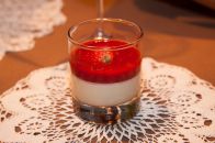 Erstarrte Pannacotta, bedeckt mit blutroter Erdbeersauce (und Erdbeere)